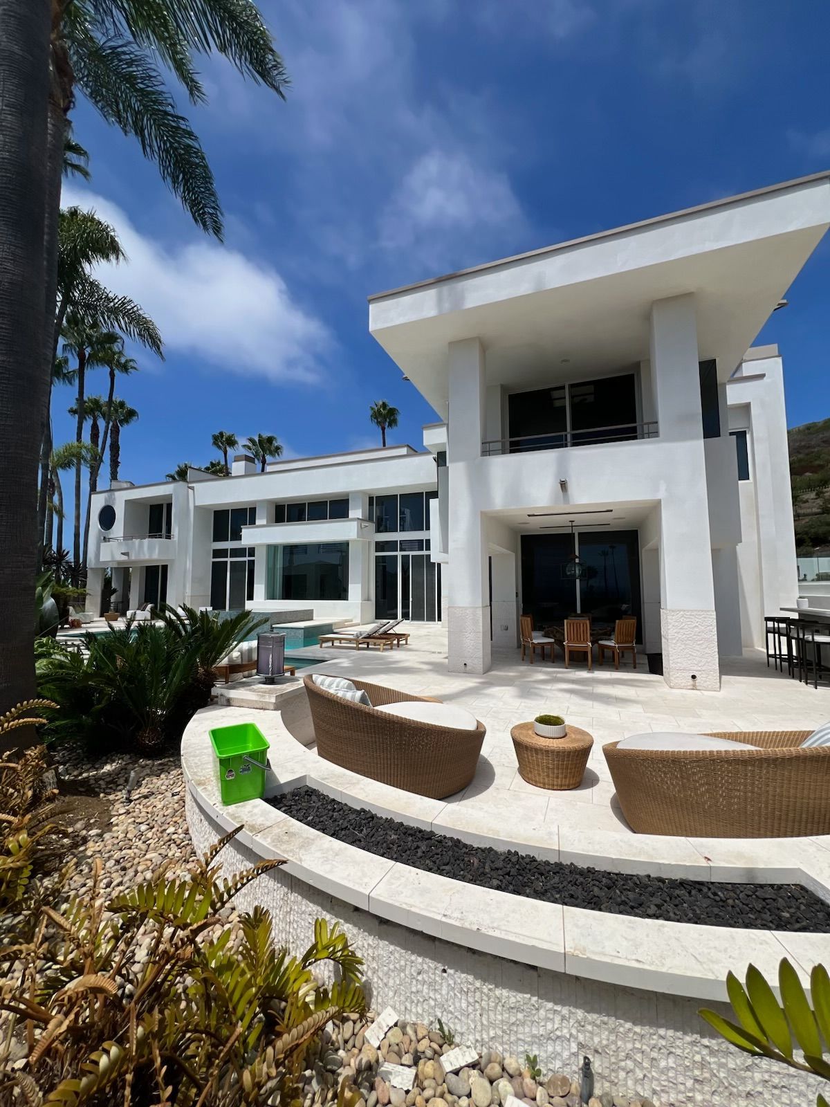 Modern white seaside villa with terrace, curved steps, and blue sky