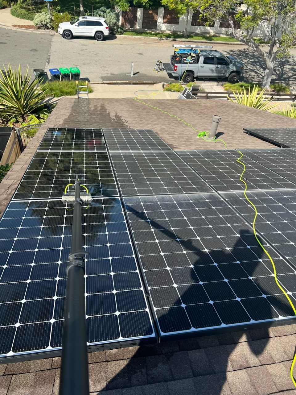 Solar panels laid across a driveway with equipment and a truck in the background.