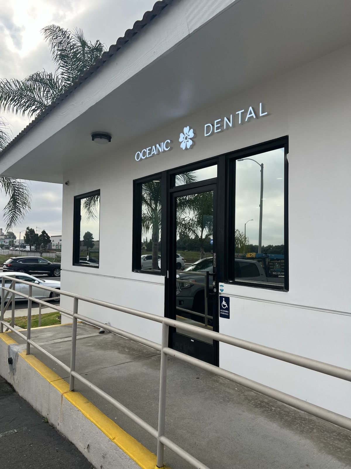 Outside view of O2 NYC Dental clinic entrance with ramp, white facade, and black windows