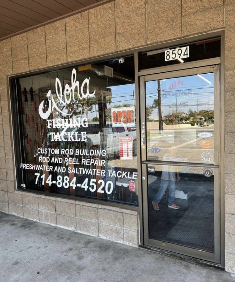 Storefront window for Aleha Fishing Tackle with service signs and phone number; glass door at right.