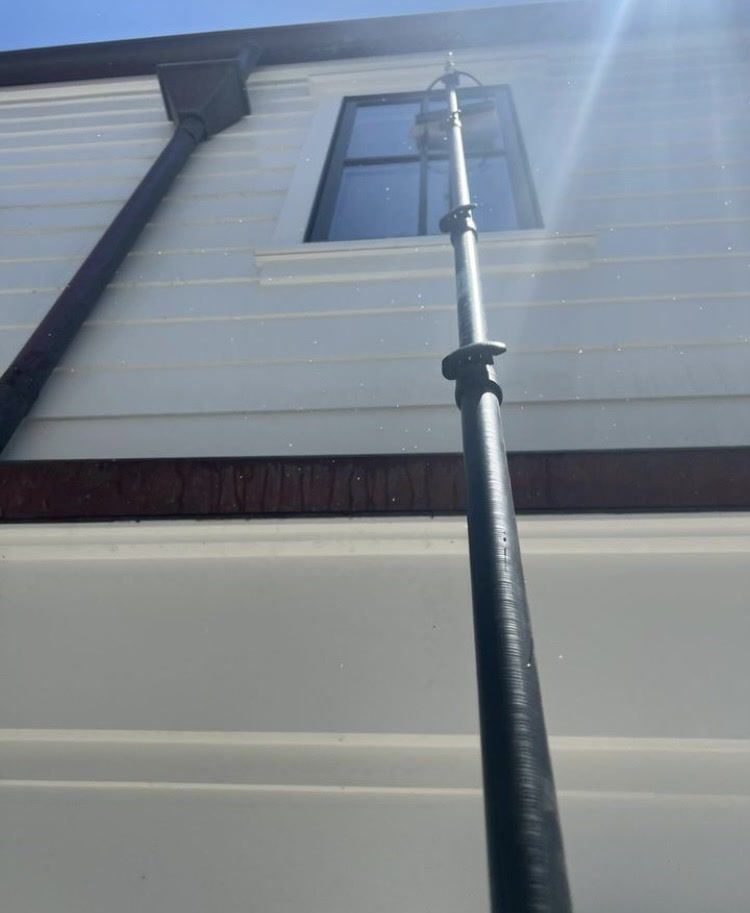 House exterior with white siding and a black pole reaching up to a second-floor window