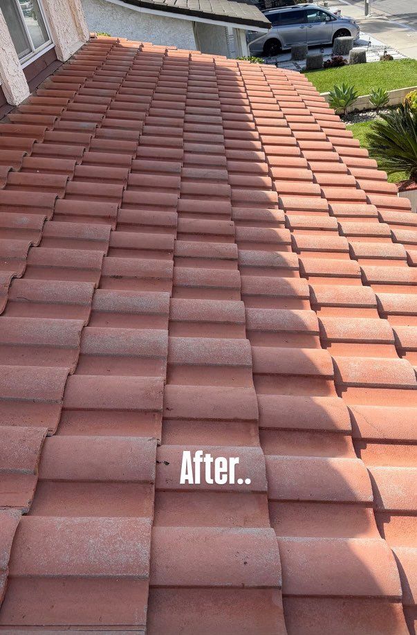Before-and-after view of a roof with cleaned red clay tiles, showing a brighter right side.