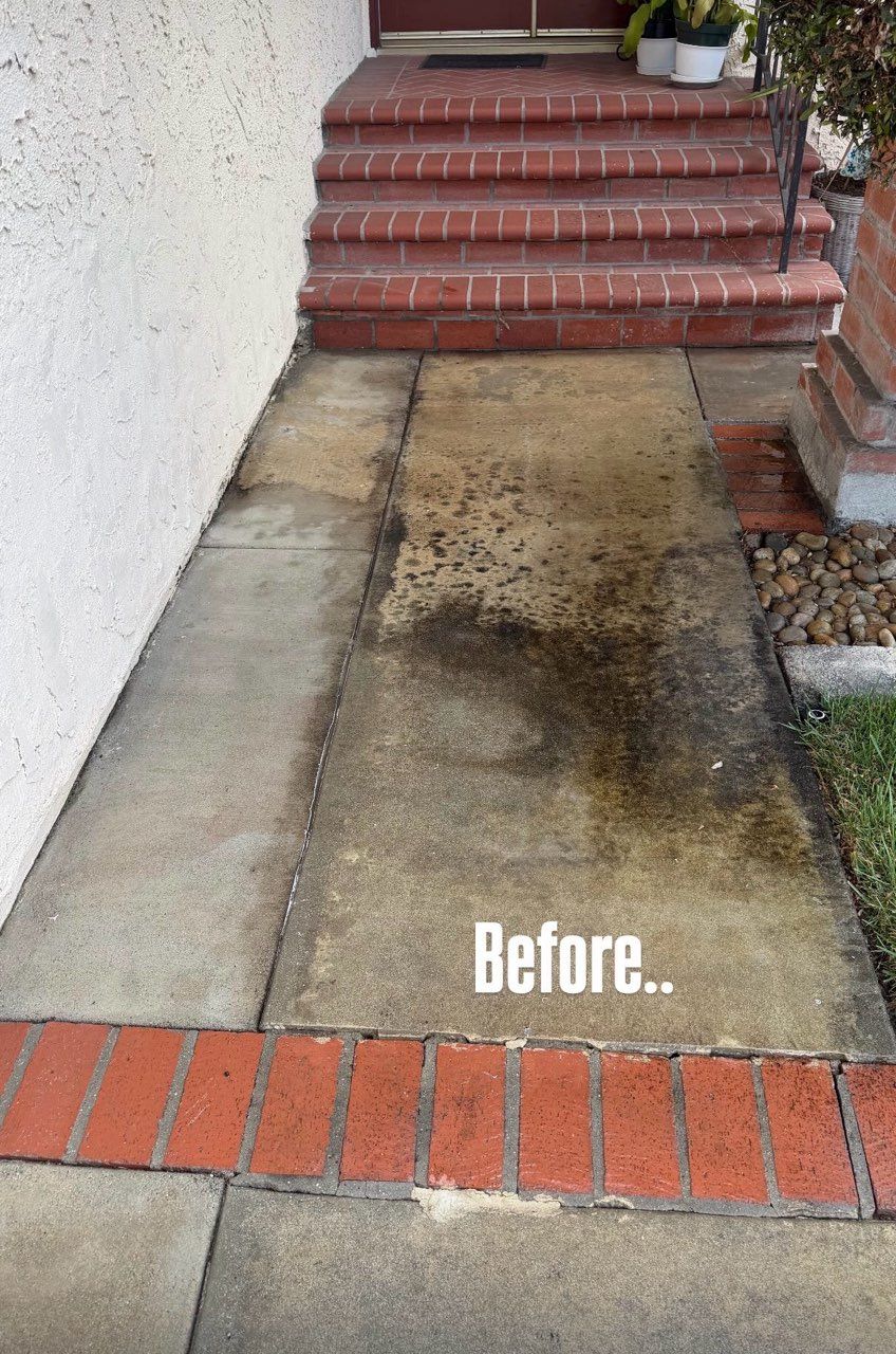 Concrete walkway before pressure washing, stained and dirty beside red brick steps