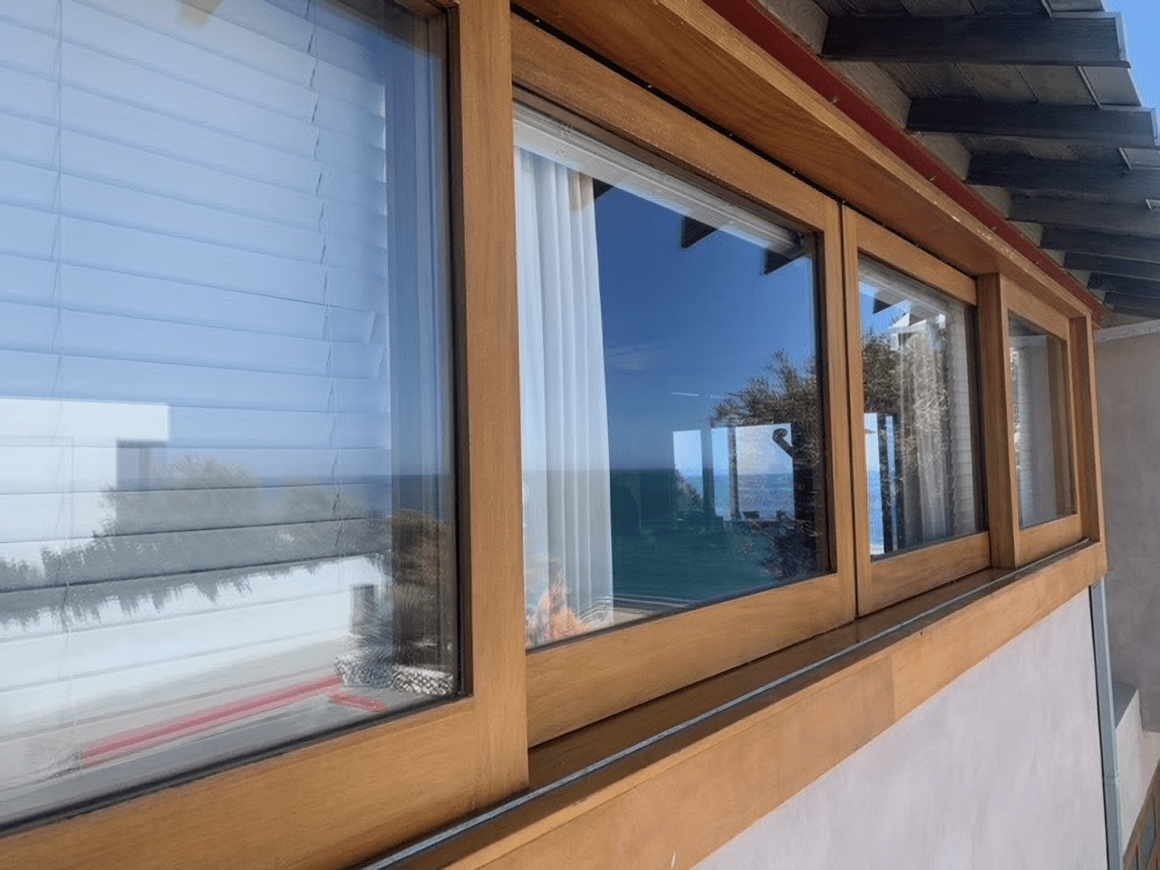 Wood-framed sliding windows reflecting a blue sky on a building exterior