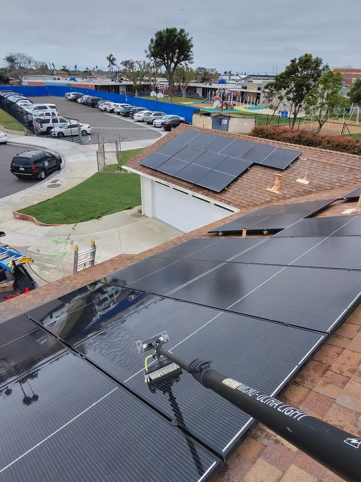 Solar panels on a rooftop overlooking a parking lot and buildings on a sunny day.