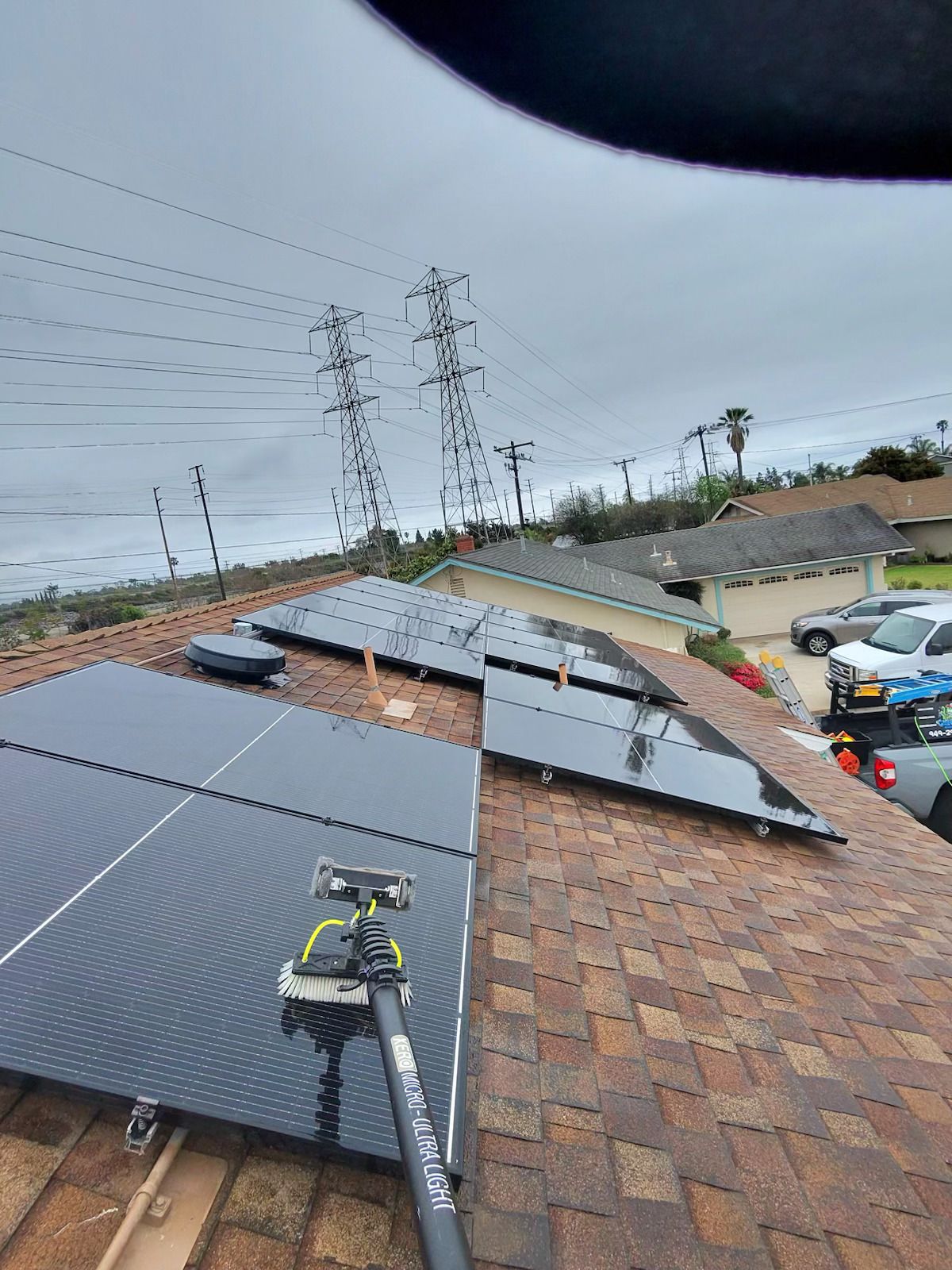 Solar panels on a brick roof with a worker in the foreground under a cloudy sky.