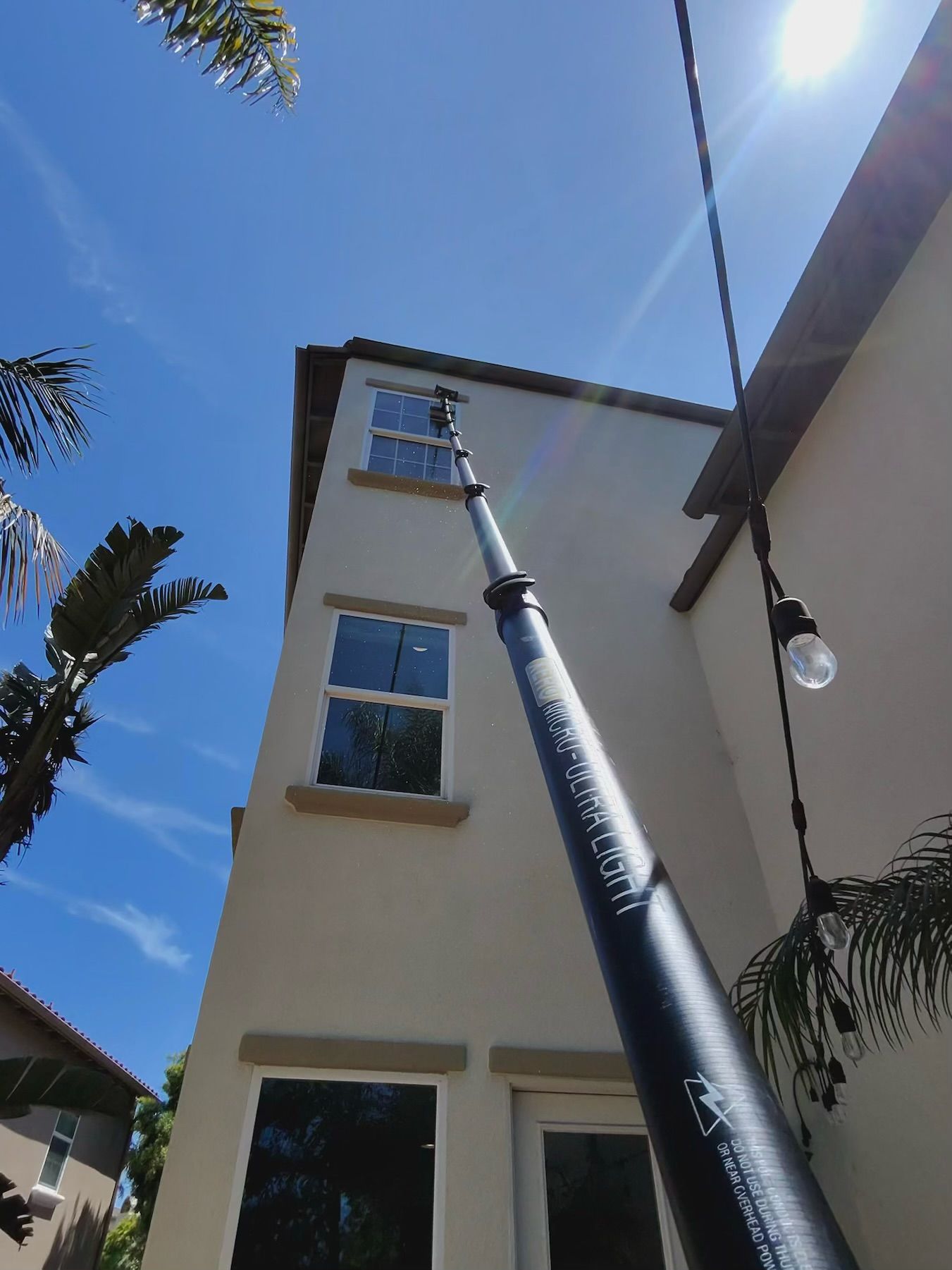 Tall building viewed upward with a blue sky, sun, and a streetlight pole in the foreground.