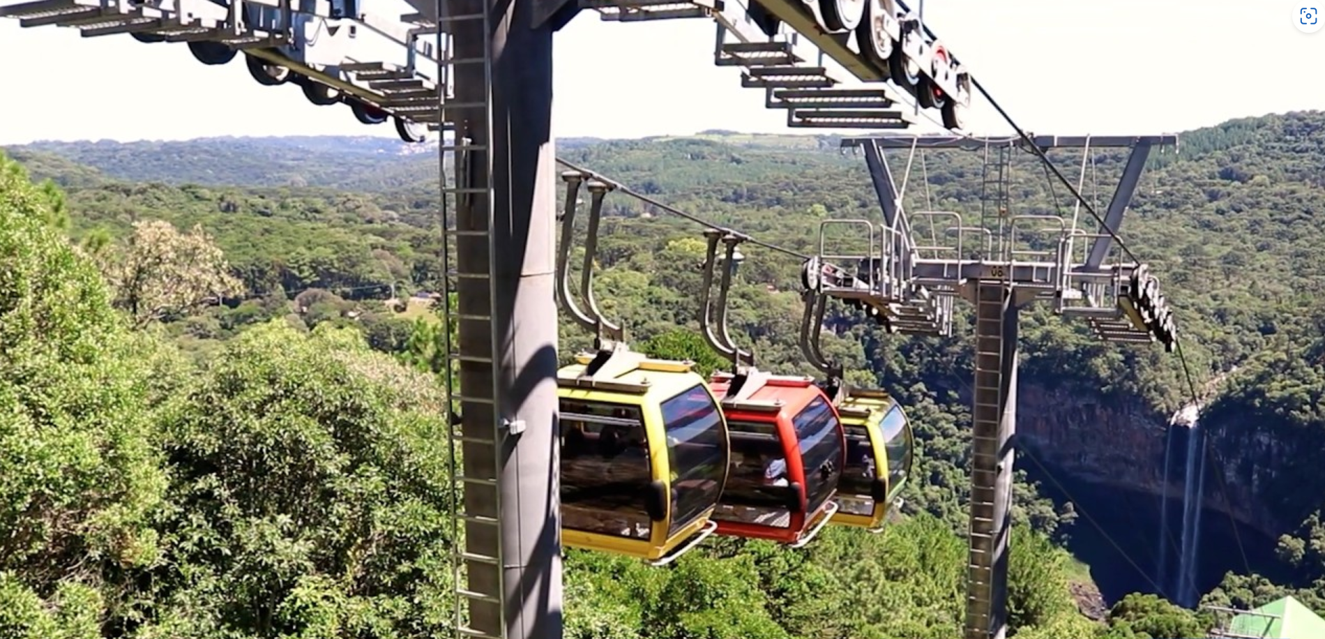 Cabines coloridas de teleférico cruzando um vale arborizado em um teleférico de montanha.