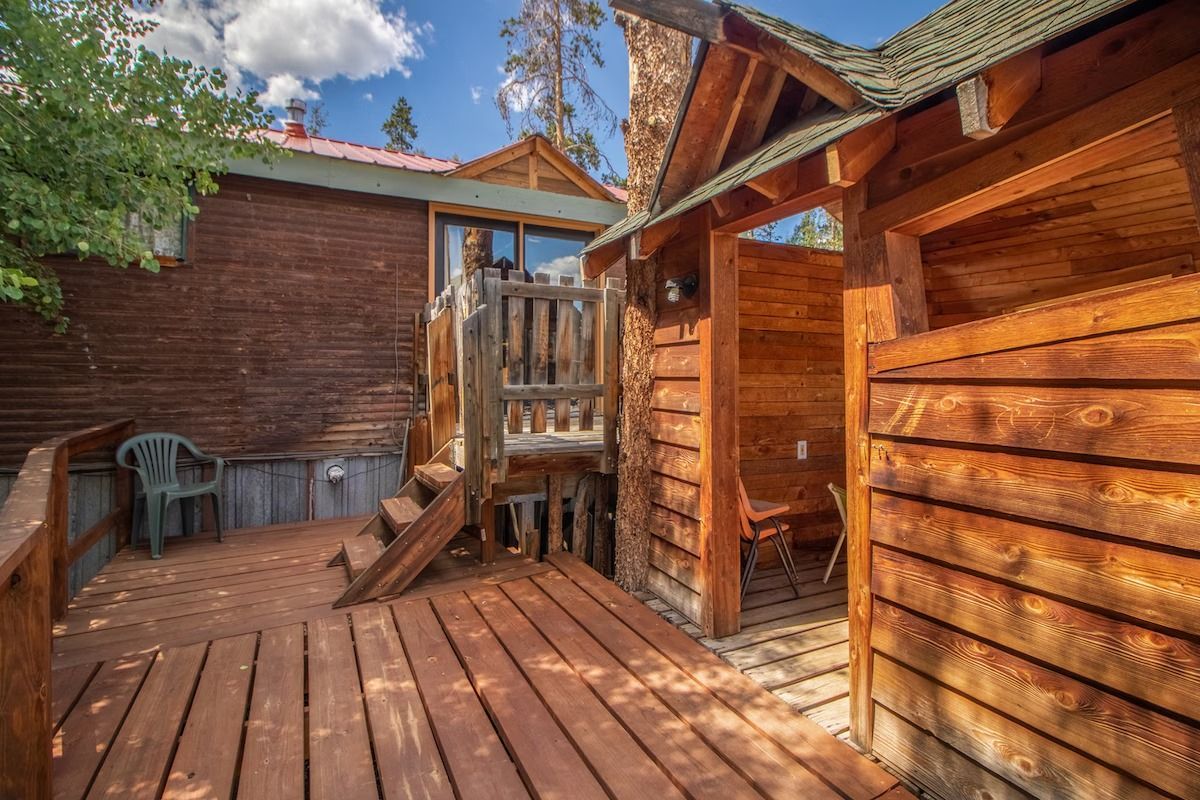 Wooden deck and rustic log cabin exterior under a blue sky with clouds