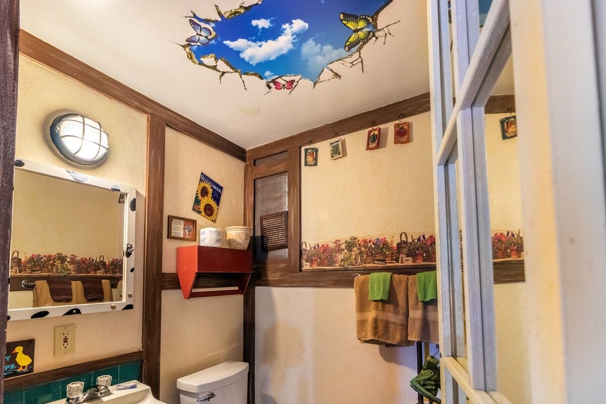 Small bathroom with skylight, wall mirror, sink, toilet, and towel rack.