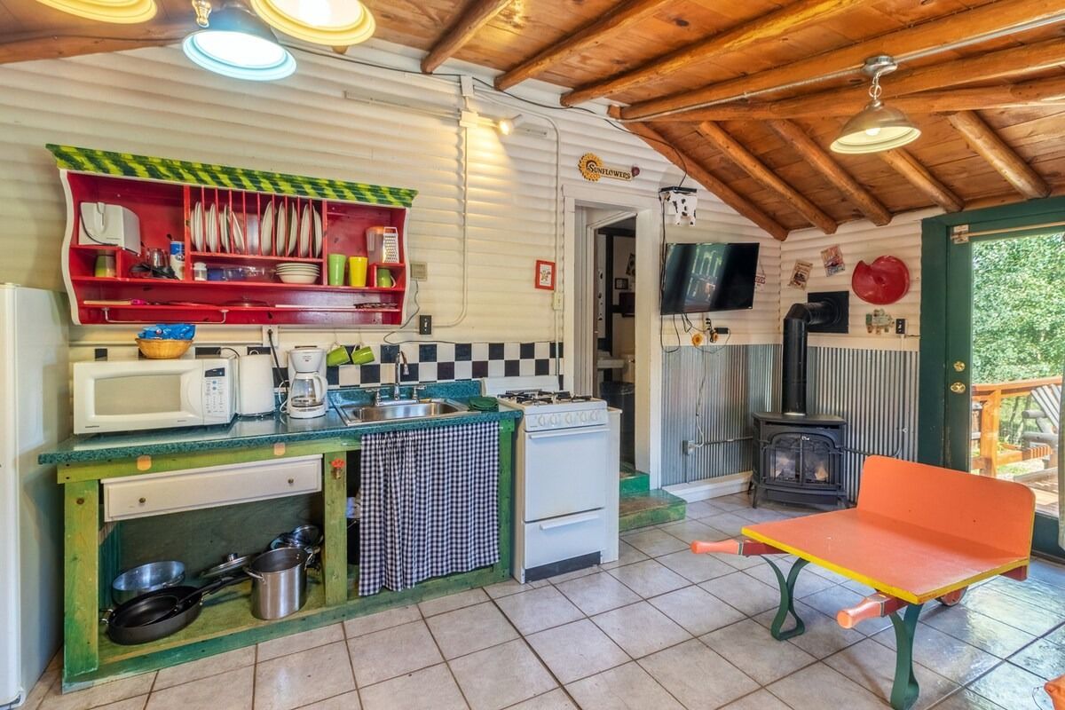 Cozy kitchen with green cabinets, tiled floor, wood ceiling, and orange bench by a sliding glass door