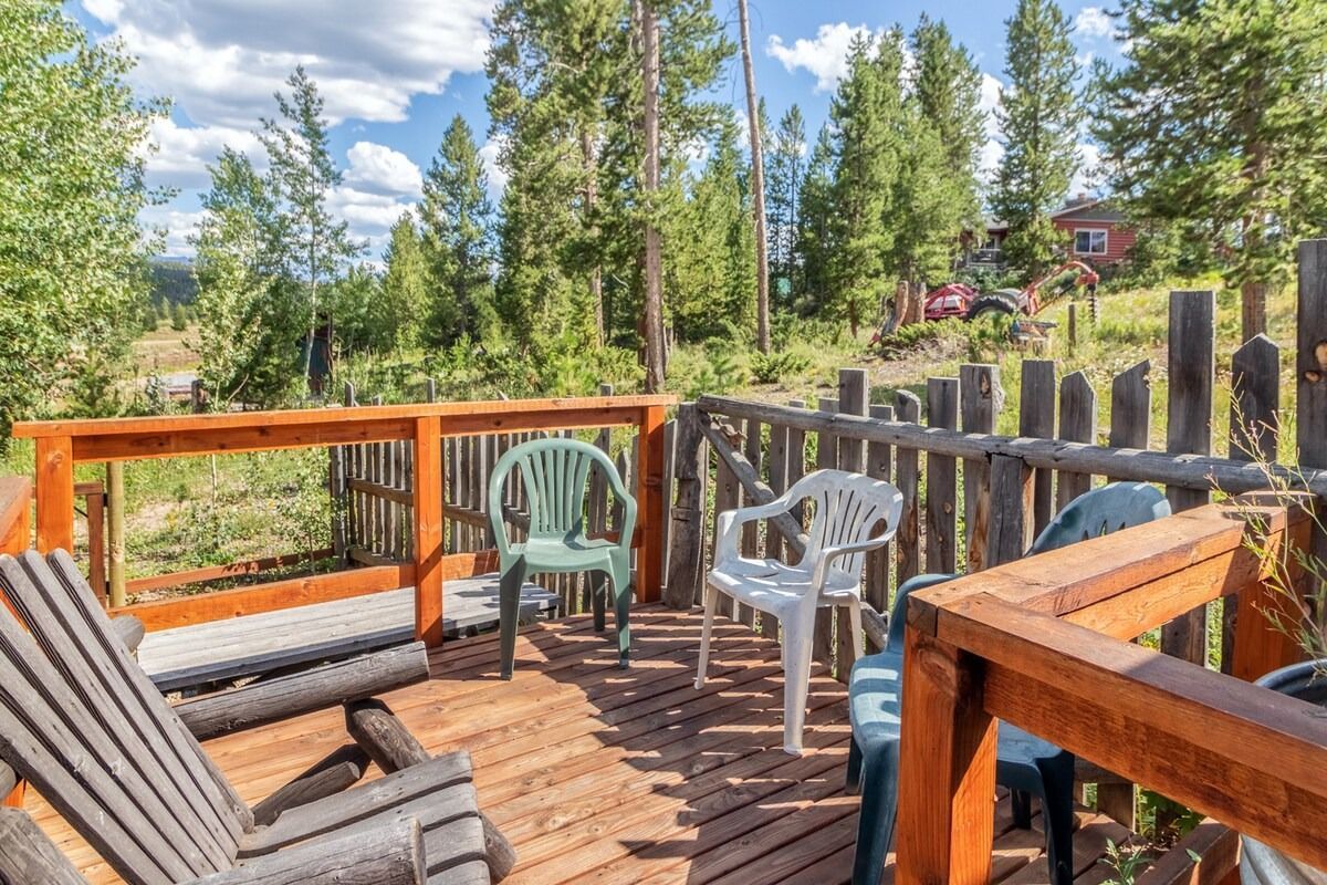 Wooden deck with plastic chairs overlooking a forest of tall pine trees