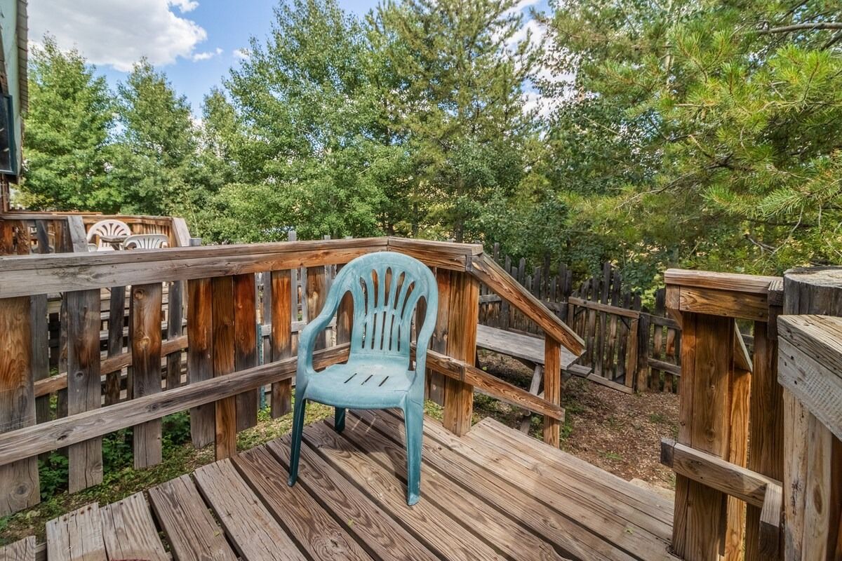 Turquoise chair on a wooden deck overlooking trees and a wooded yard