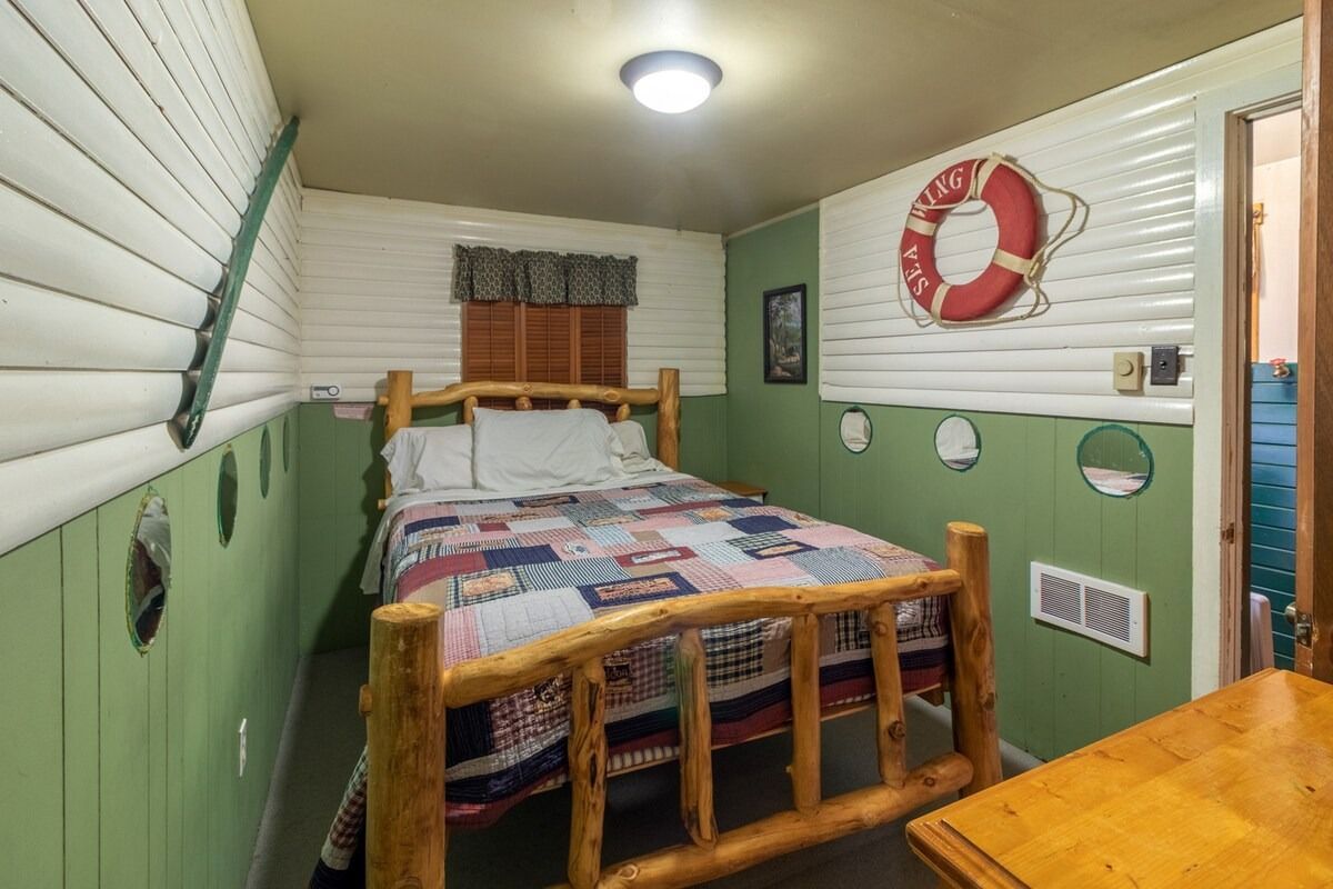 Small nautical-themed bedroom with single bed, green walls, and a life preserver on the wall