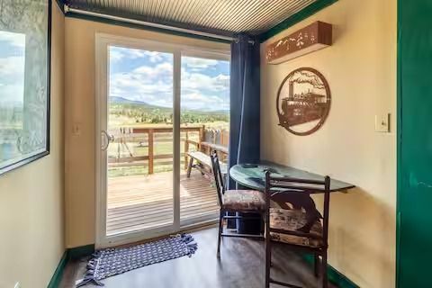 Small entryway with desk and chair opening to a deck and mountain view