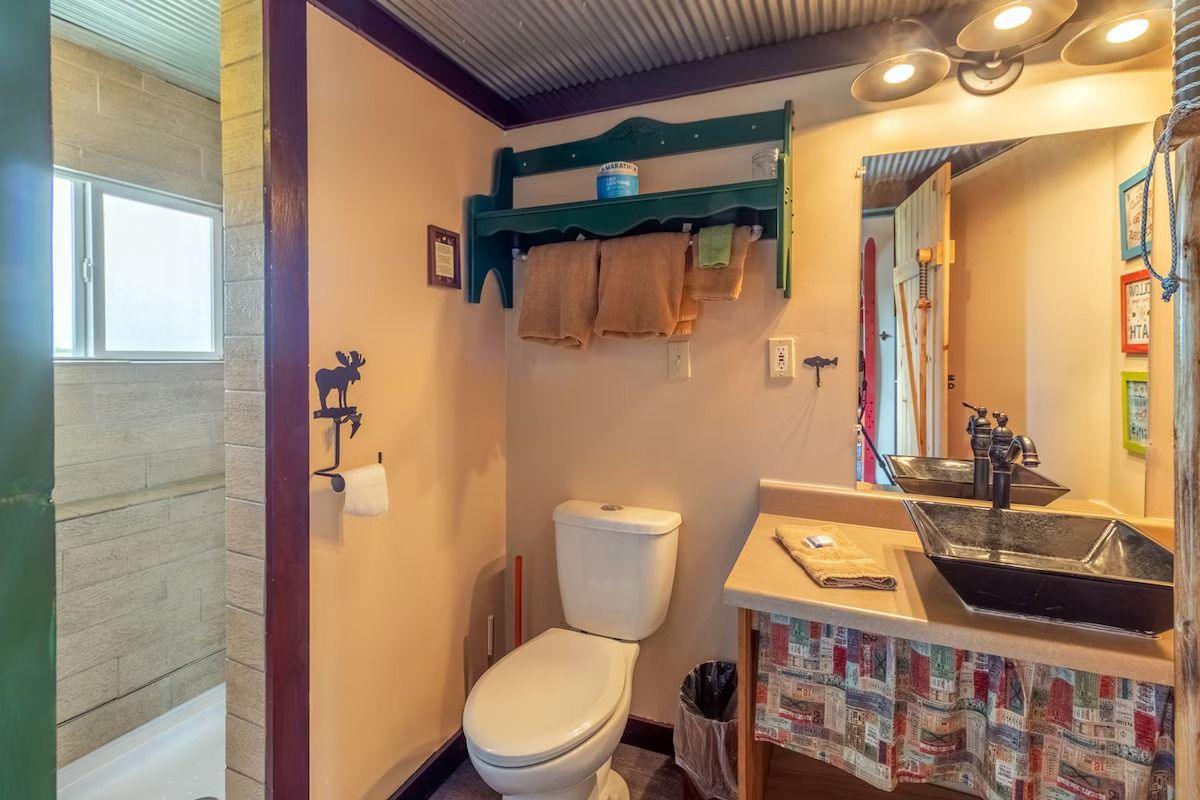 Small bathroom with toilet, vanity sink, mirror, and shower stall in warm lighting