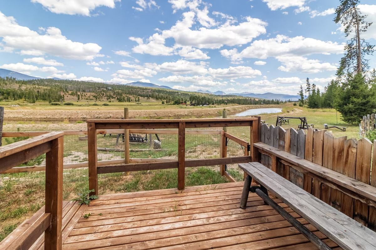 Wooden deck overlooking a marsh and river with mountains and cloudy sky beyond