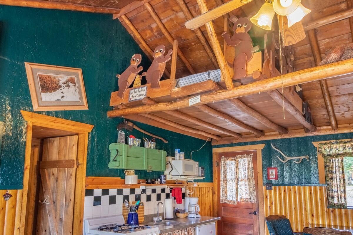 Cozy rustic kitchen with teal walls, wood beams, hanging fan, and small tiled counter