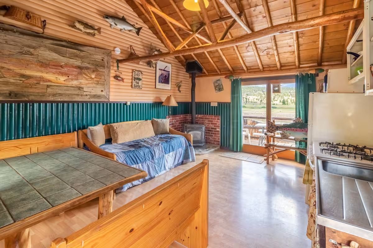Rustic cabin bedroom with bunk beds, wood-paneled walls, and a window view of greenery
