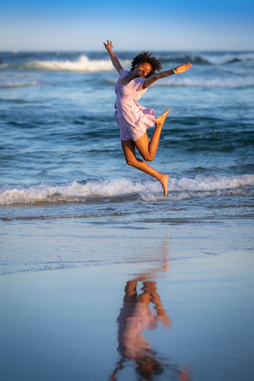 Woman jumping happily on beach.