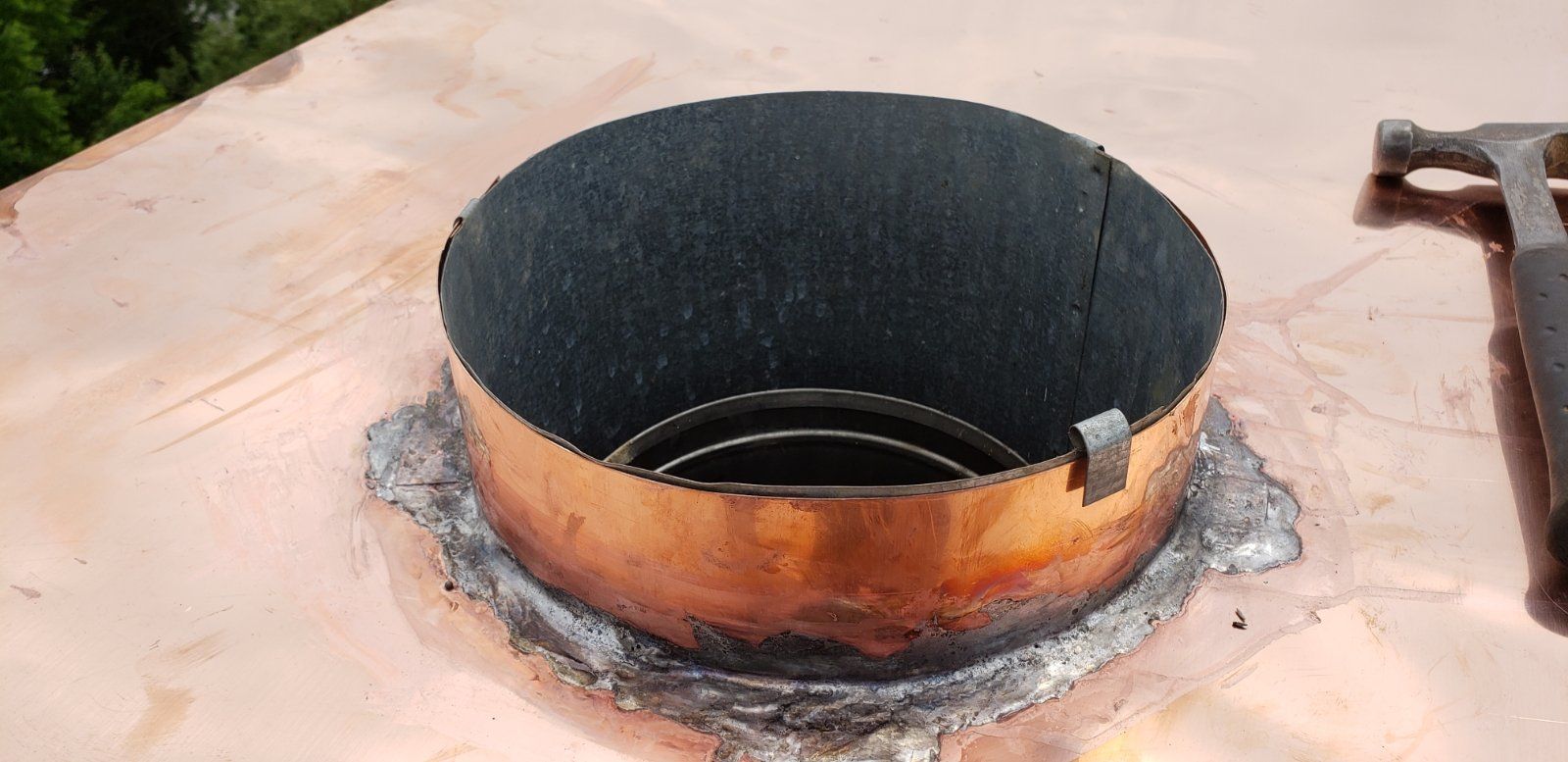 A copper pipe is sitting on top of a copper roof.
