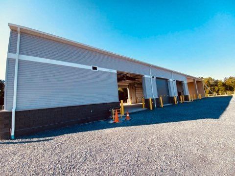 A large building with a lot of doors is sitting on top of a gravel lot.