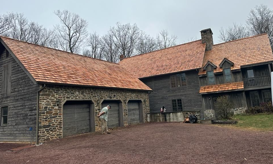 A large house with a copper roof and a stone garage