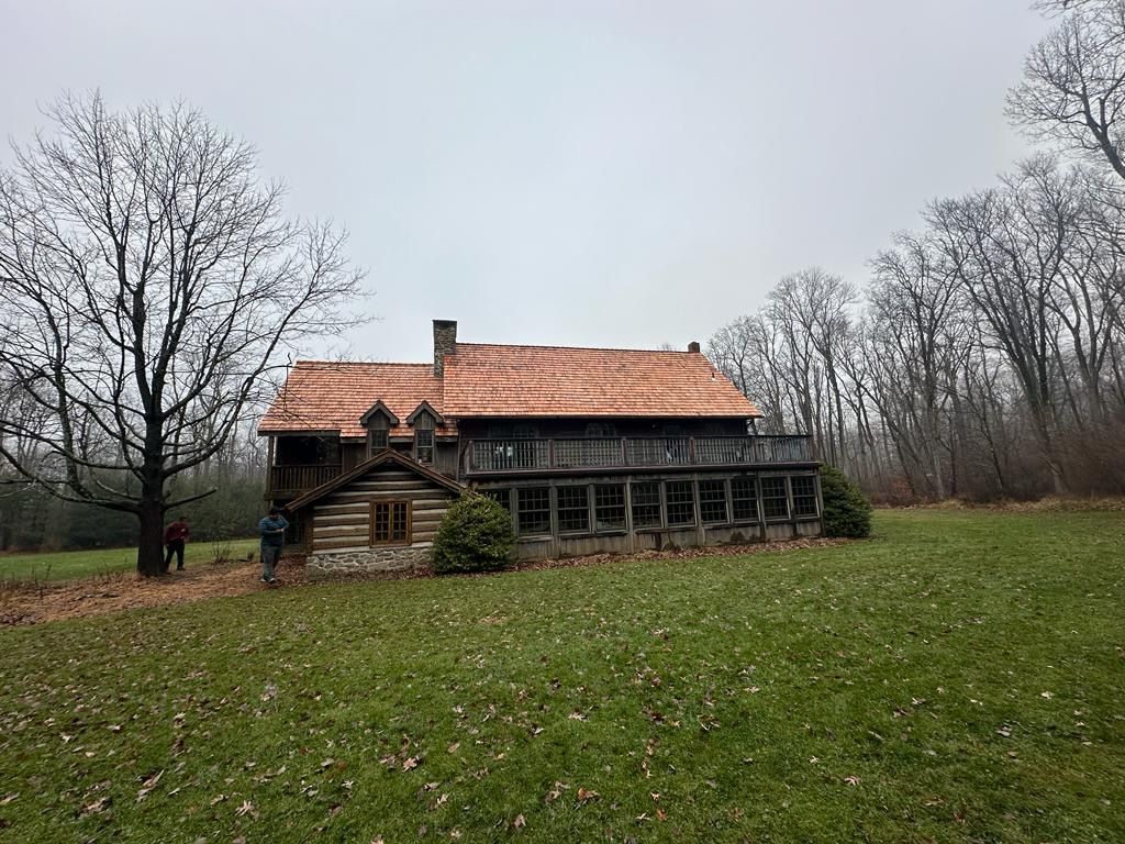 A log cabin is sitting in the middle of a grassy field.