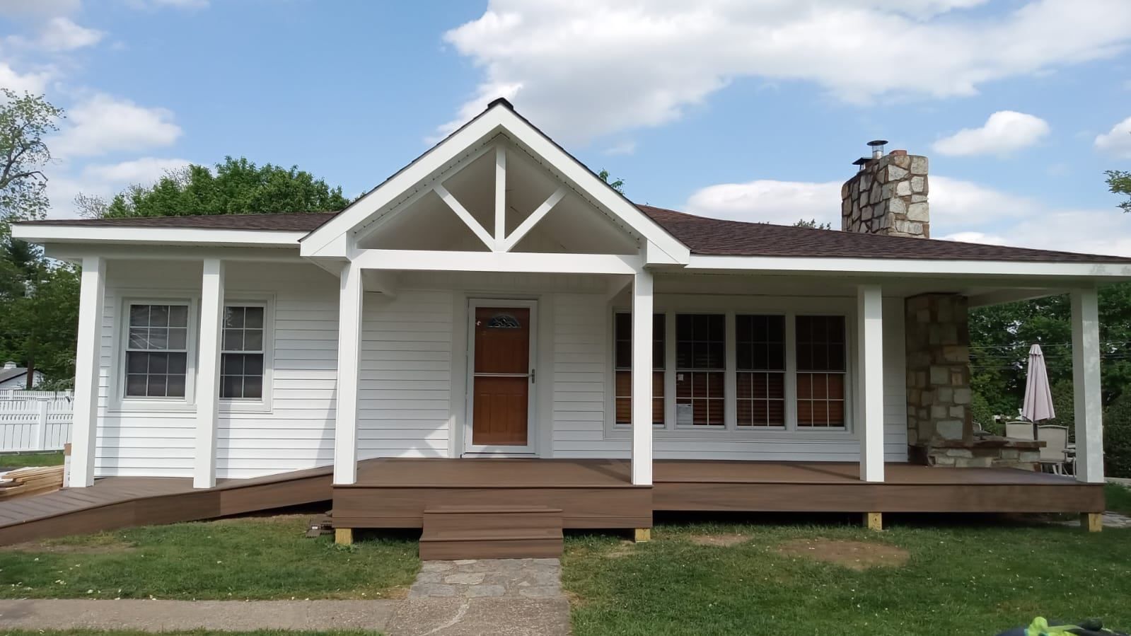 A white house with a porch and a stone chimney