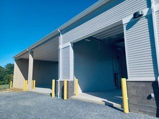 A building with a large garage door and a lot of gravel in front of it.
