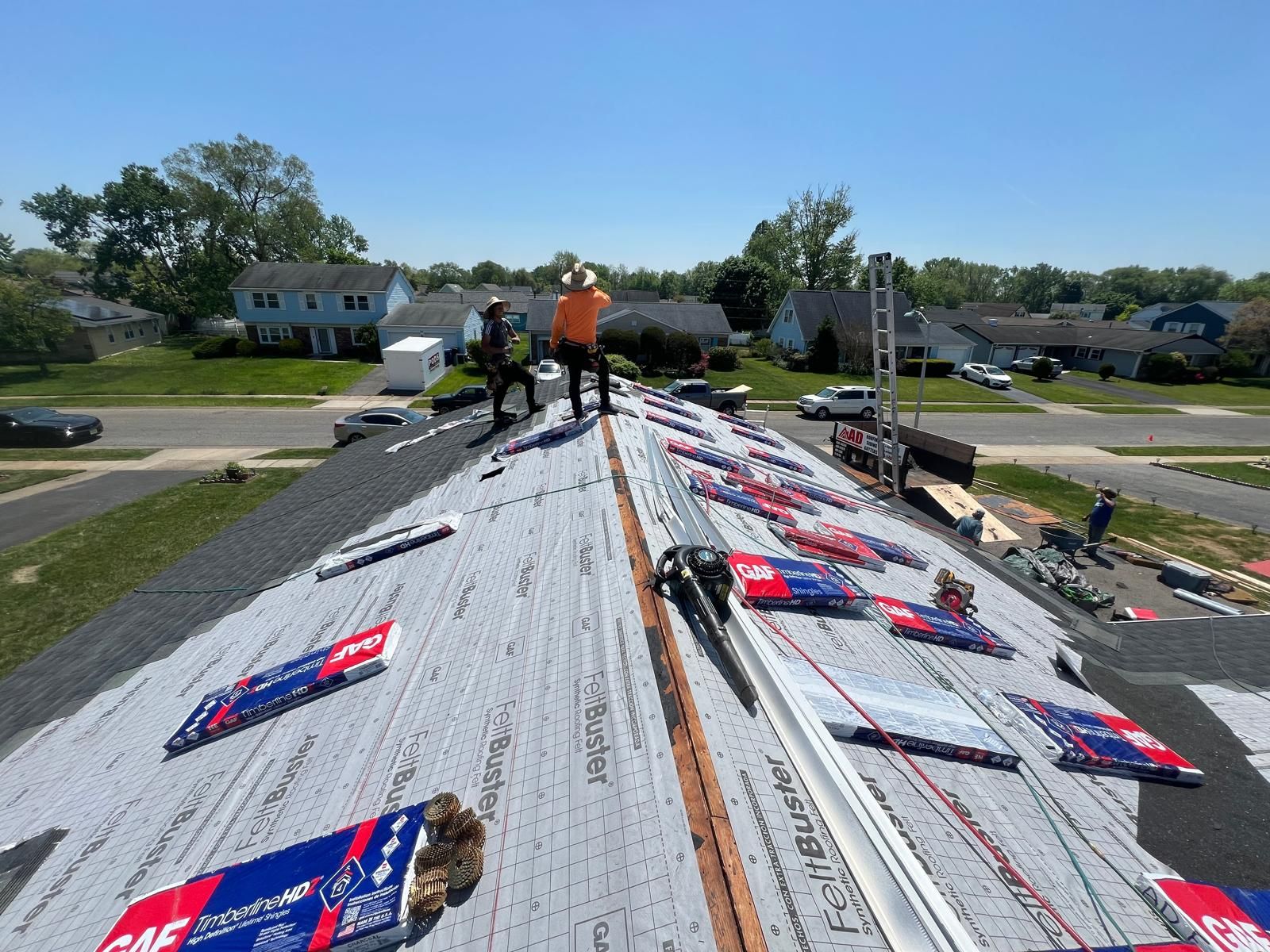A Group of People Are Standing on Top of a Roof — Burlington, NJ — AD Roofer Siding & Gutters