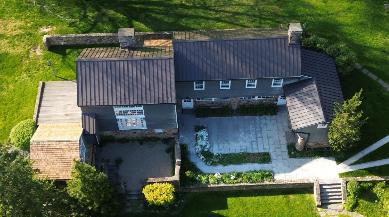 An aerial view of a house in the middle of a lush green field.