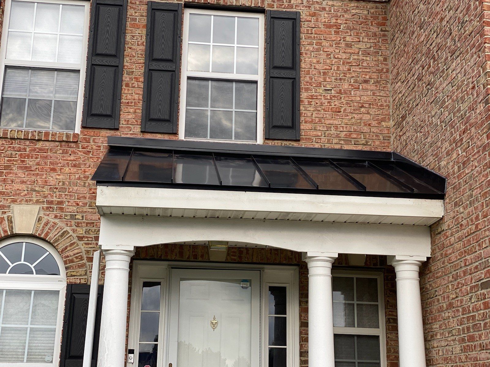 A brick house with a porch and black shutters