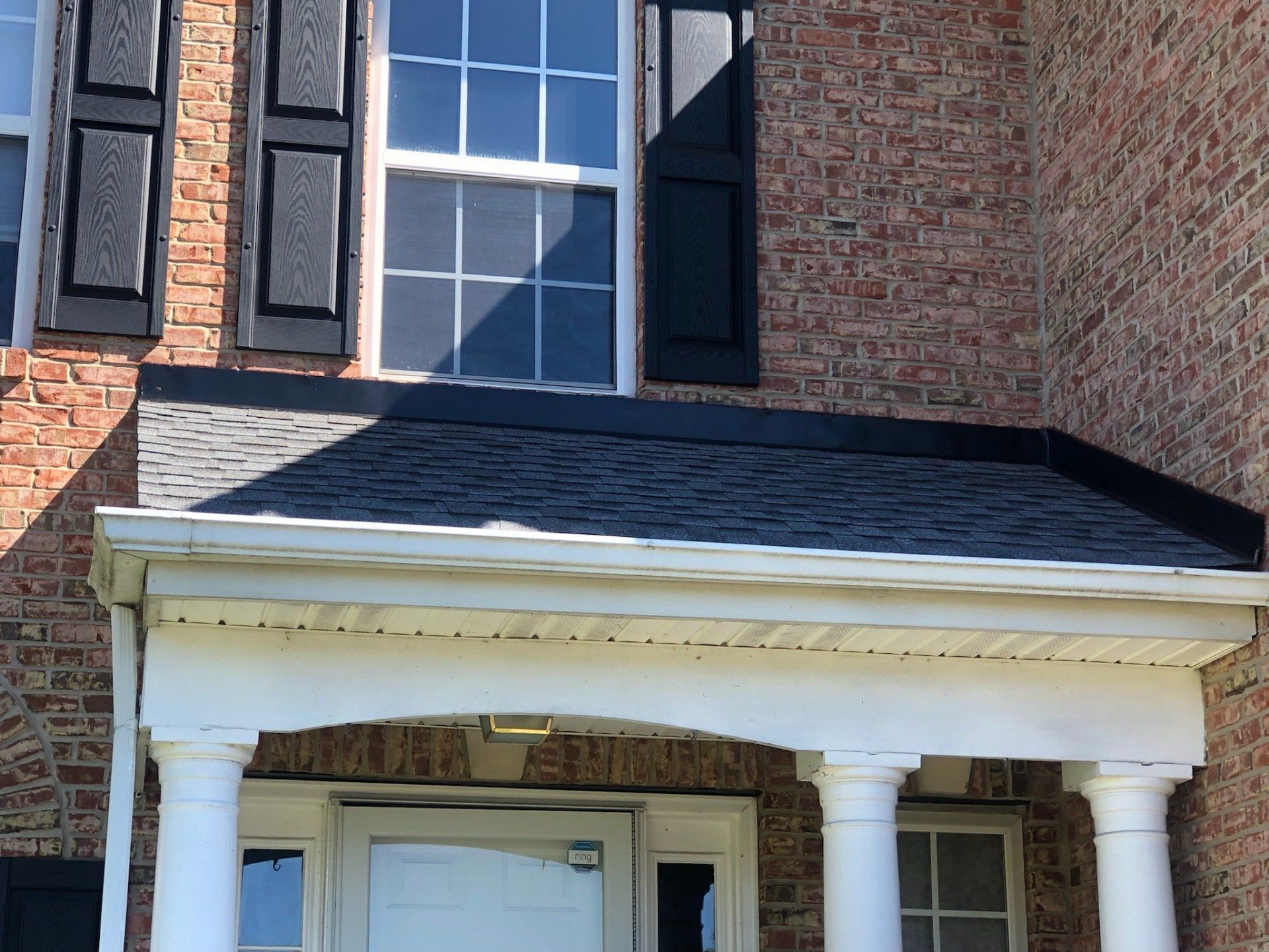 A brick house with a porch and black shutters