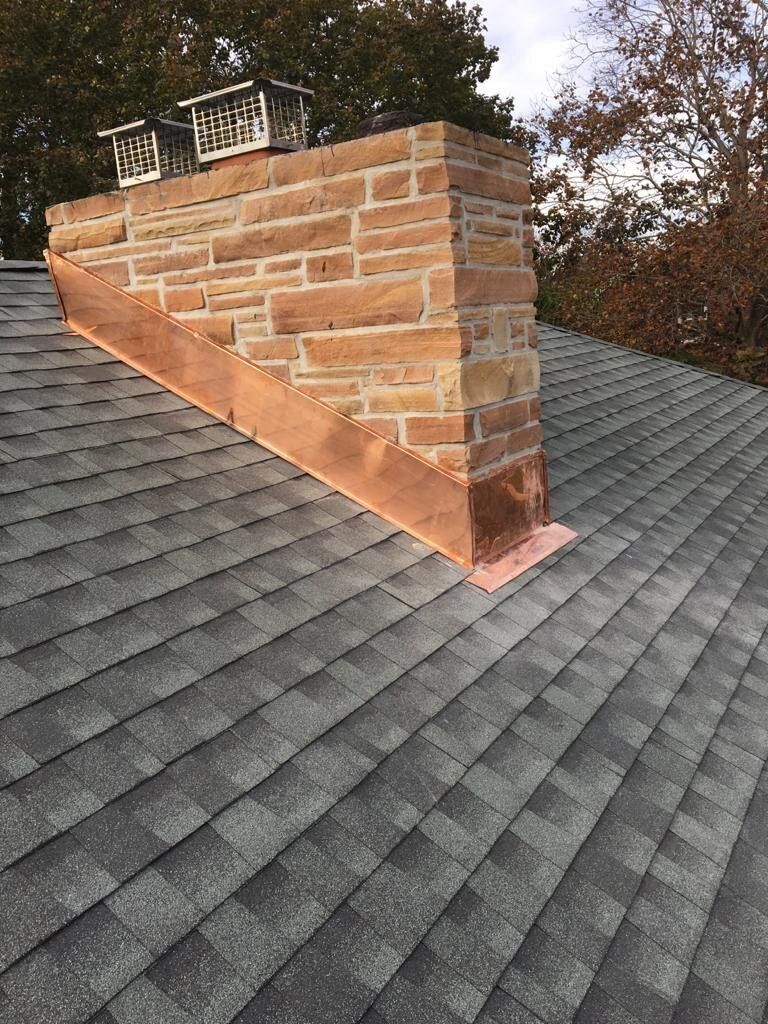 A brick chimney is sitting on top of a roof.
