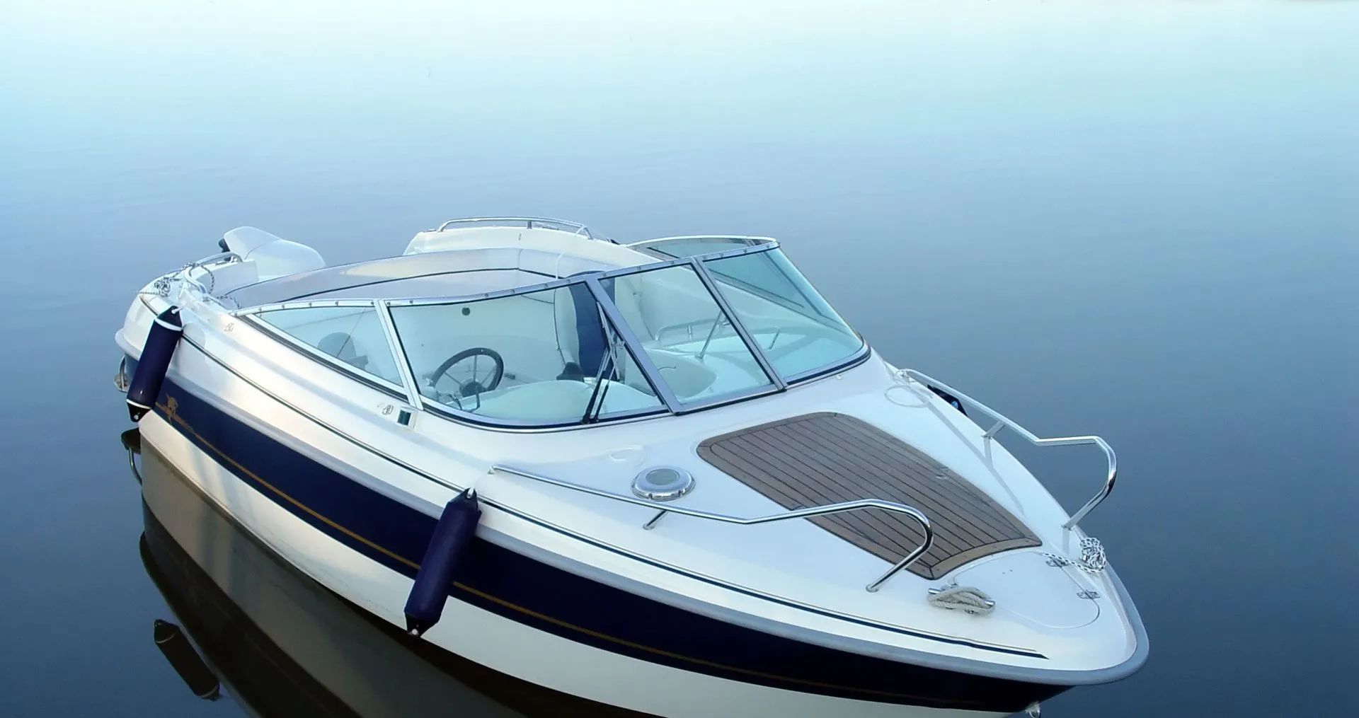 White and blue motorboat floating on calm water.