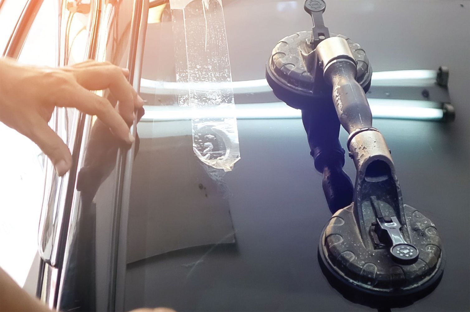 Person using suction cups to apply film to a car window.