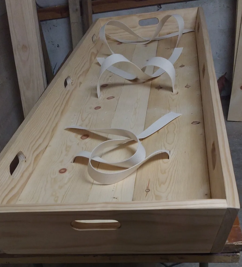A wooden box with handles and ribbons on it