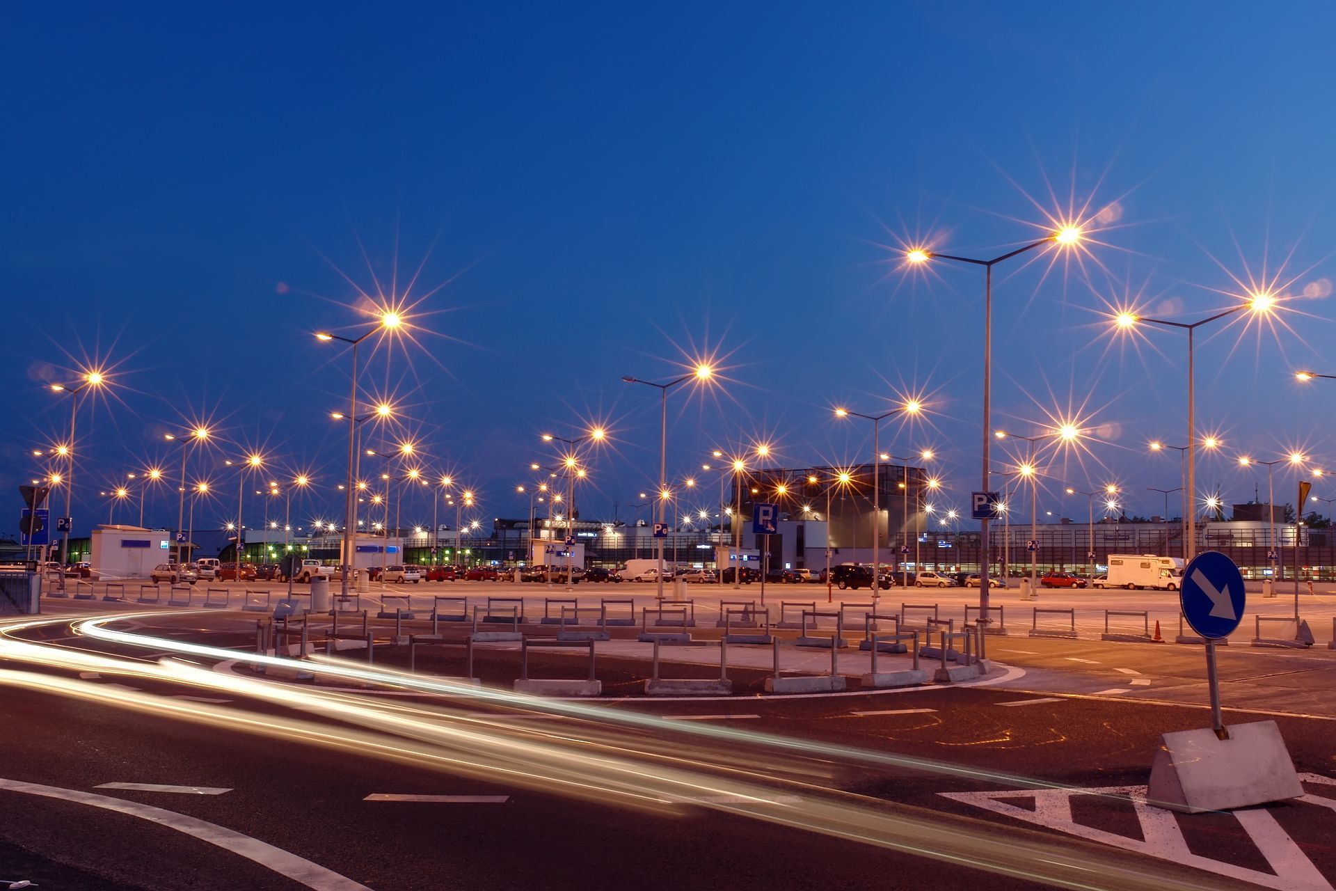 A roundabout at night illuminated by multiple streetlights creating starburst effects.