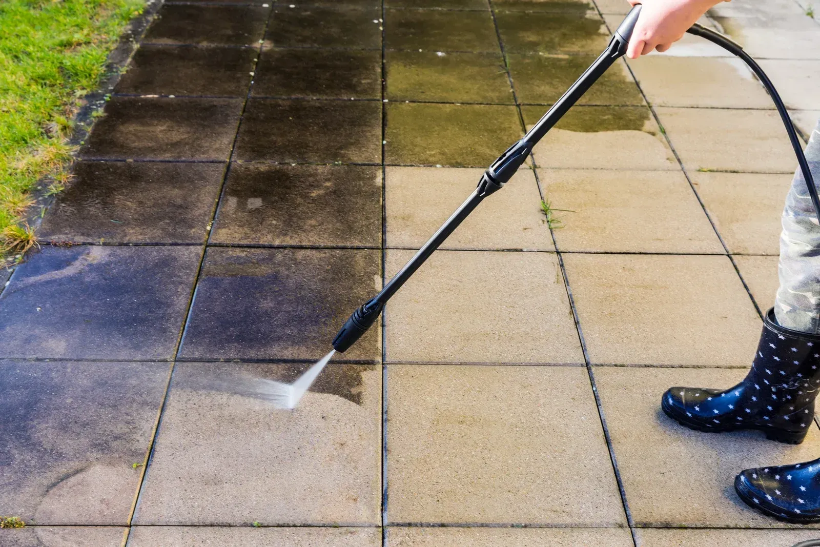 Pressure washing a concrete patio, half clean and half dirty.