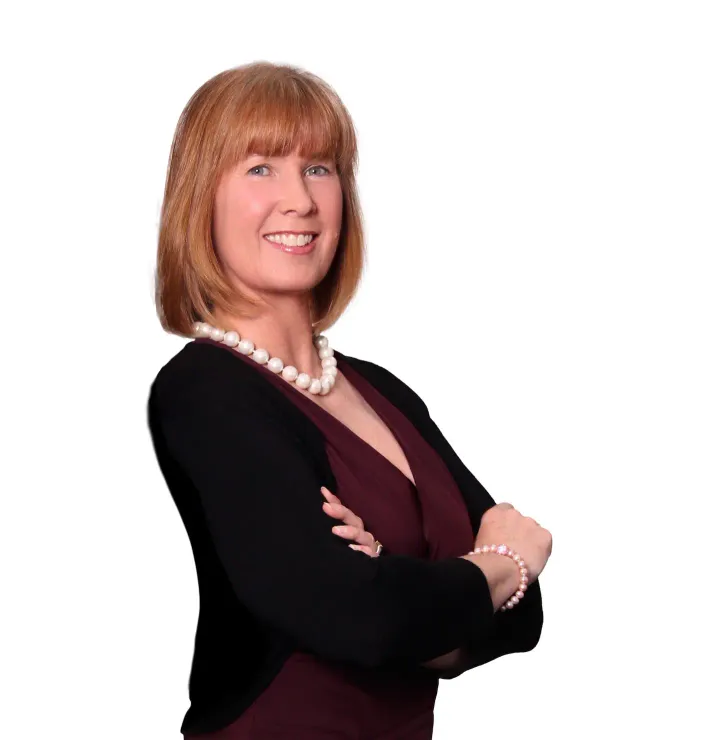 A woman with her arms crossed wearing a pearl necklace