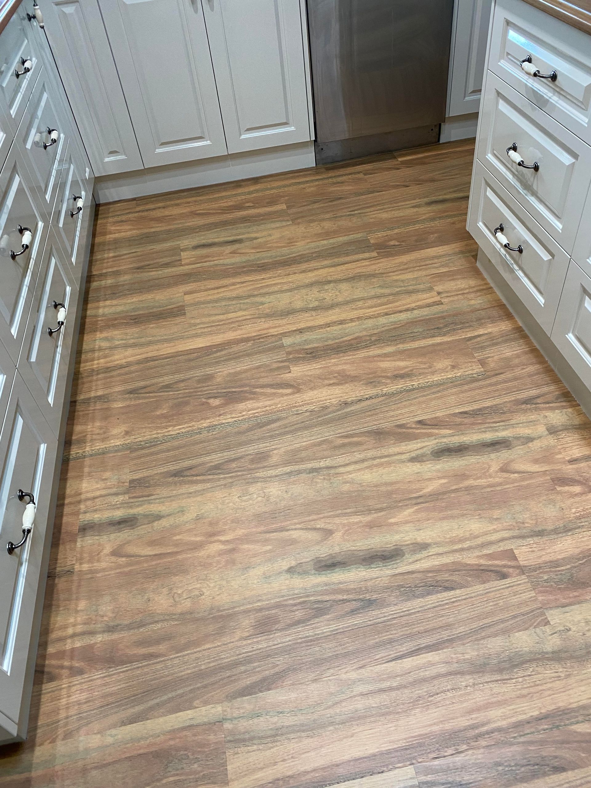 Wood-look flooring in a kitchen with white cabinets.