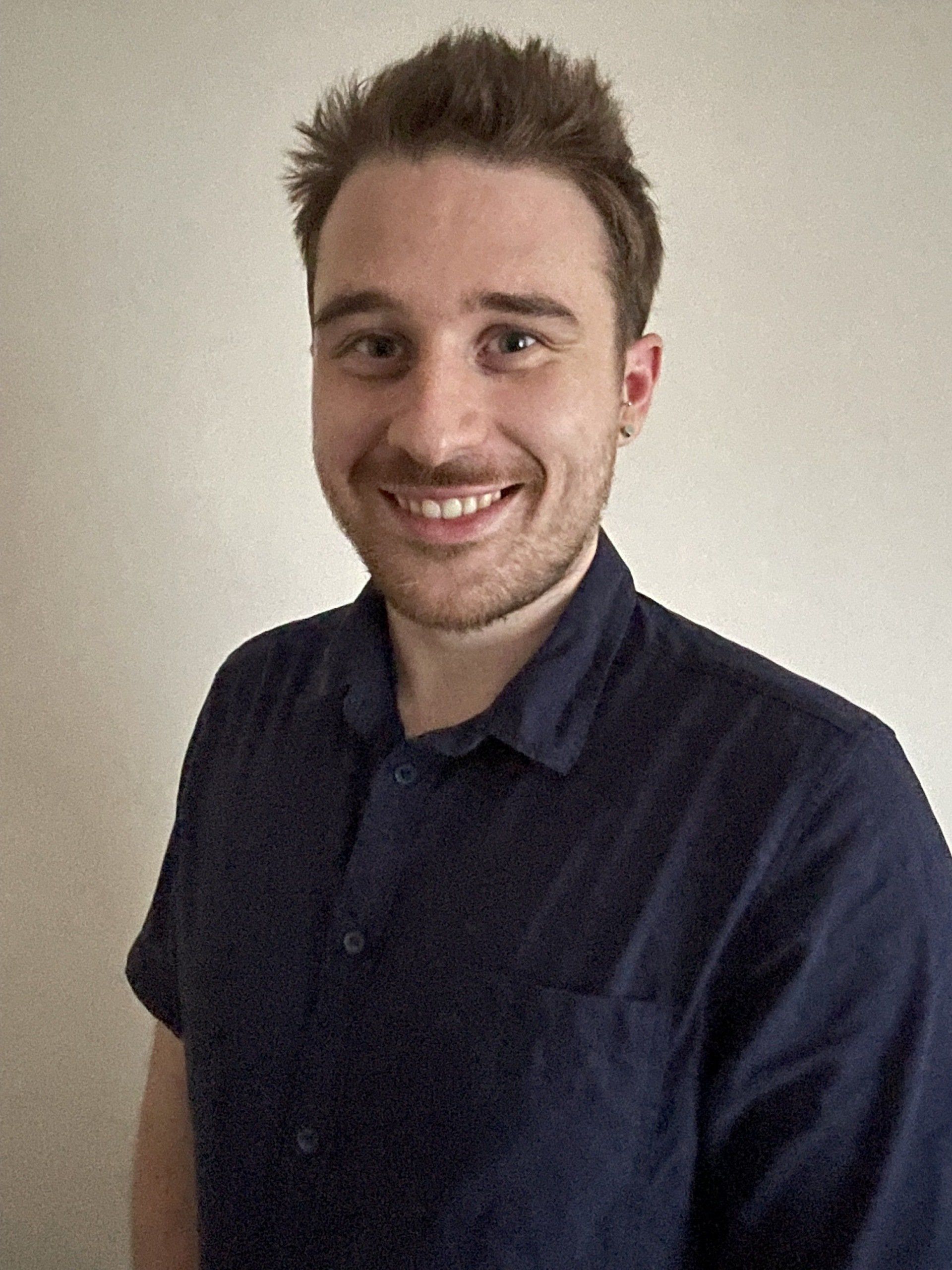 A man in a blue shirt is smiling for the camera.