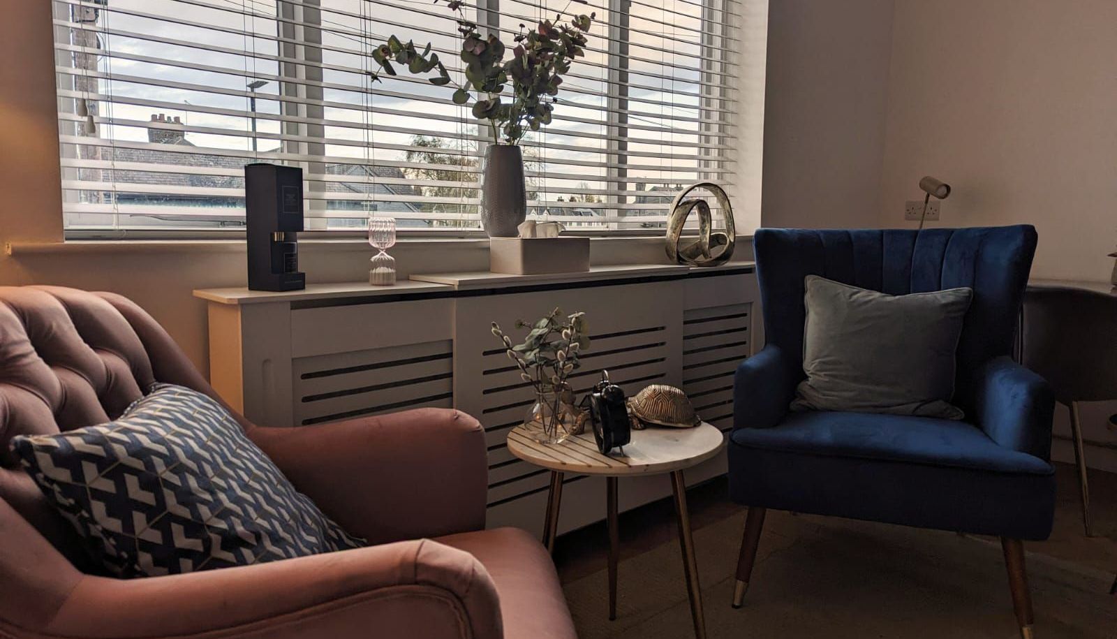 A living room with two chairs and a table in front of a window.