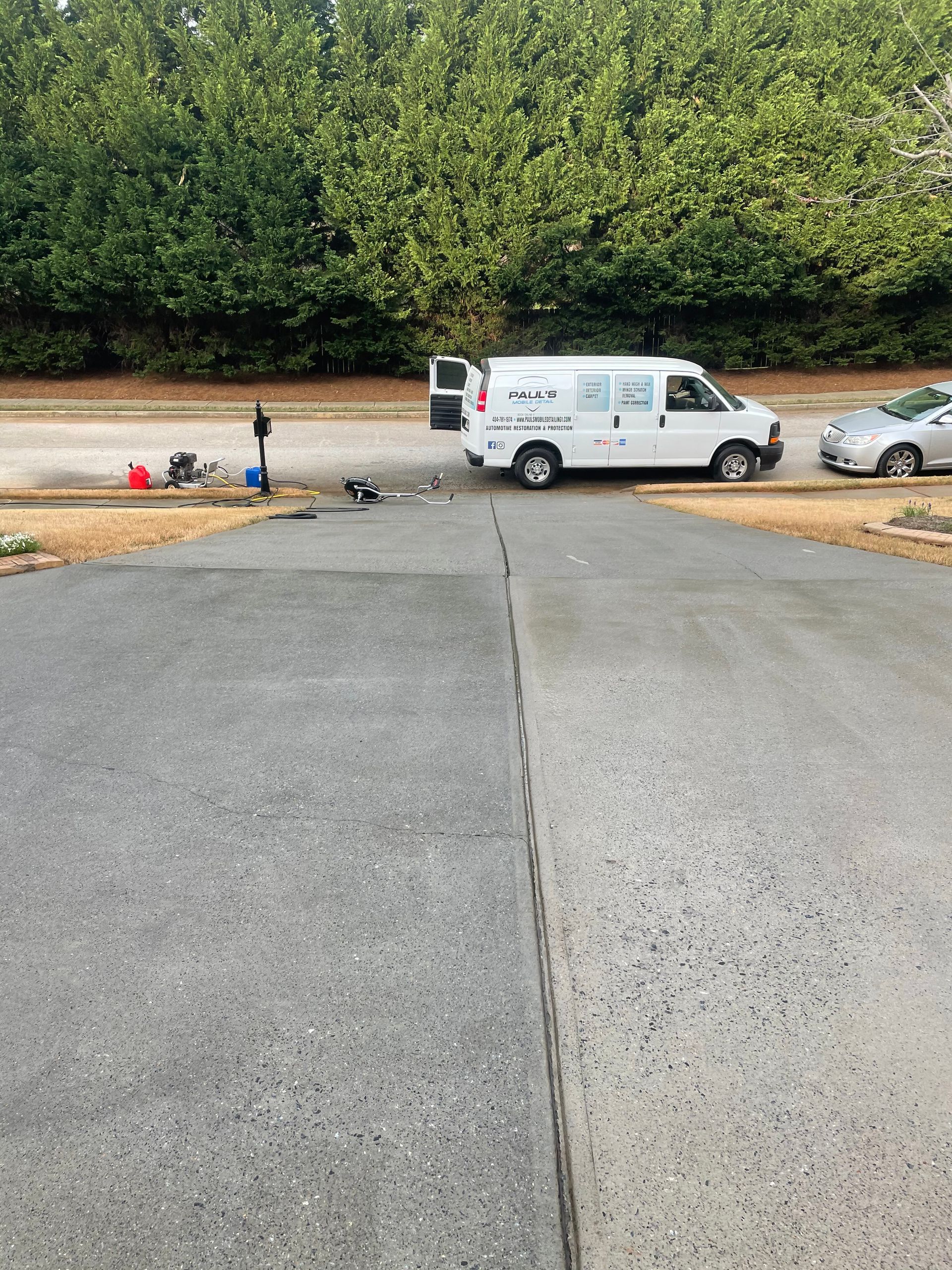 A white work van parked on a driveway with freshly poured concrete next to older concrete.
