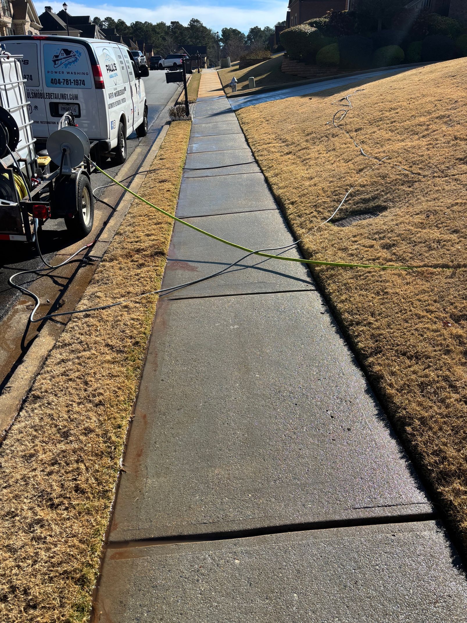 Sidewalk with utility markings and a work van parked on the side of a road.