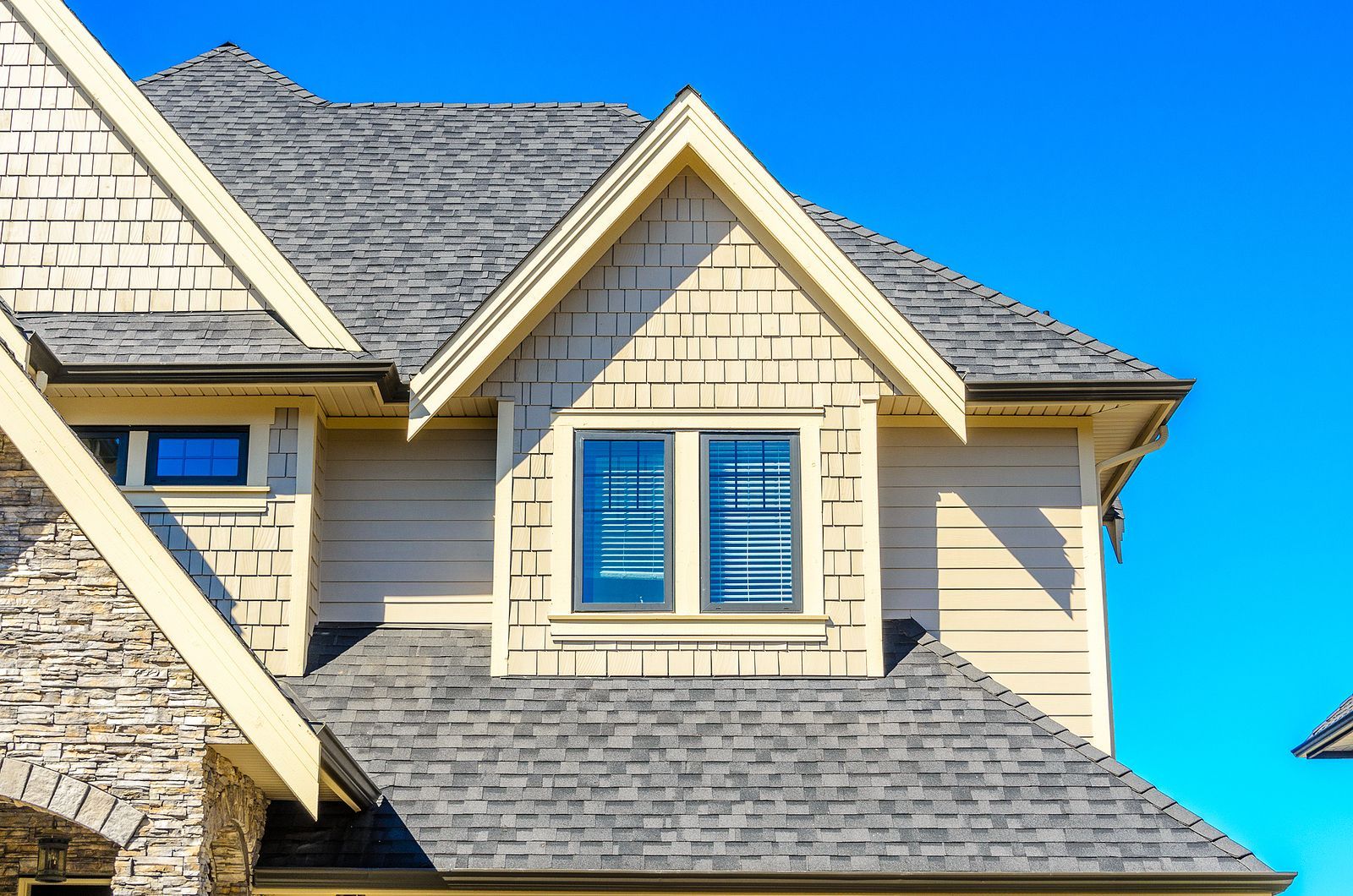 The roof of a house with a window and a blue sky in the background.