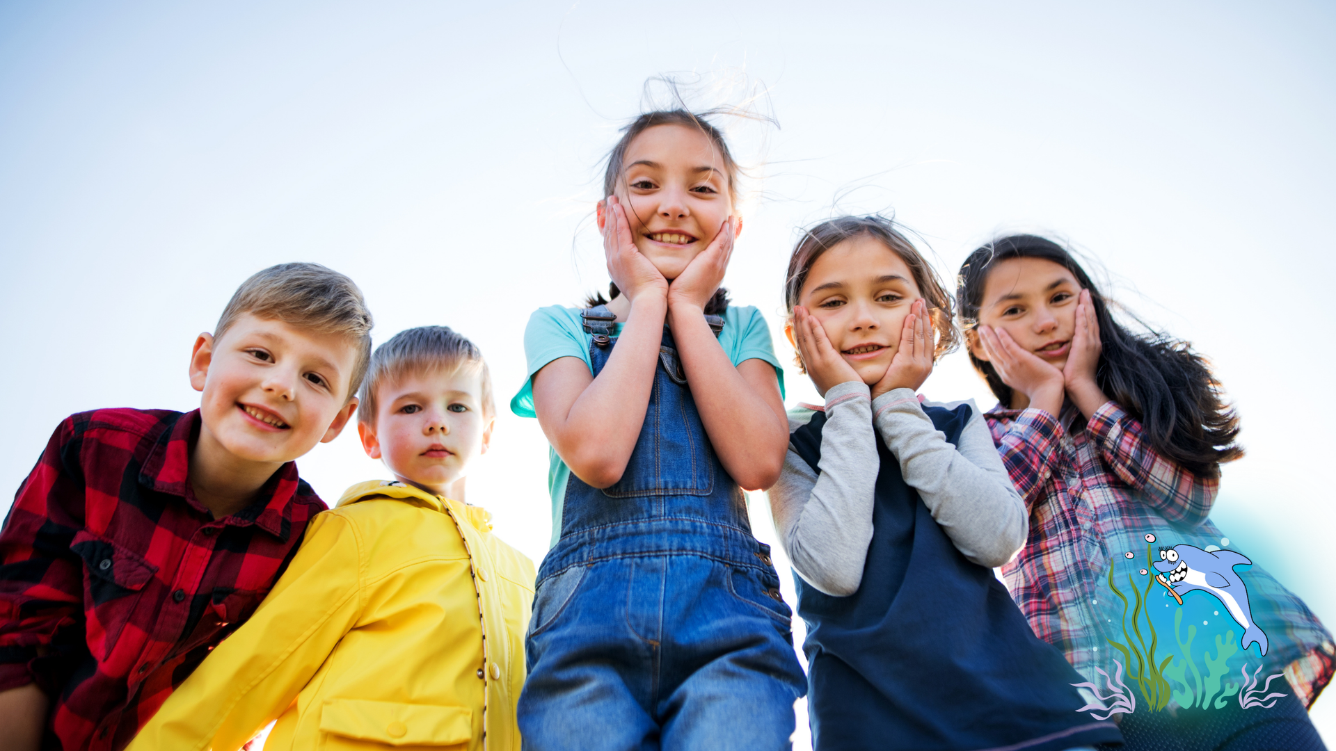 Group of five smiling children looking up, hands on their cheeks.