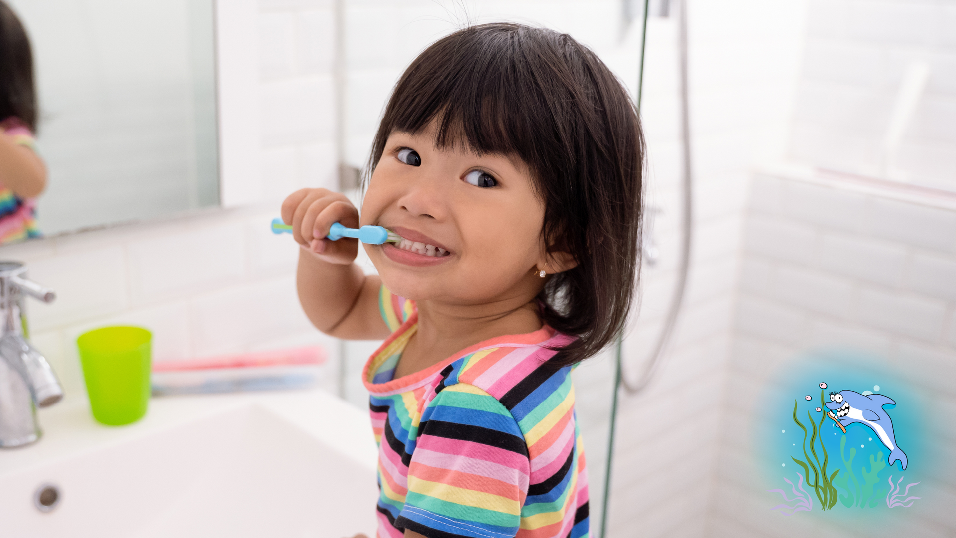 Young girl with short black hair brushing teeth in bathroom, smiling.