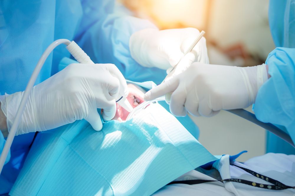 Dentist performing dental work on a patient in a medical setting.